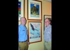 National Eagle Center Executive Director Rolf Thompson and eagle art collector Preston Cook stand beside two patriotic posters with eagles depicted on them. The two are among the 20,000 items Cook is donating to the Eagle Center Museum.