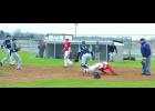 Ryan Wolfe dives head first and safely into home plate on this double steal in the bottom of the 5th inning Friday—as the ball scoots away from the catcher. Fillmore Central’s pitcher, catcher and first baseman converge on the plate and Cooper Holtorf (1) watches with his bat in hand as he waits to complete his turn at bat.
