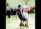 The official keeps a close eye on the action as Hope Lutheran’s Tristan Rusert closely guards W-K’s Liam Blaschko during the second half of Saturday’s game in rural Lewiston, won by the Falcons.