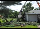 Orlon Miller of Dregney’s Tree Trimming used a bucket truck to clear away a large pine branch that plunged through the roof and siding of a garage on Eisenhower St. while Cliff Jamison worked on the ground to cut branches down to size. 