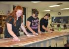 Cadettes (left to right) Lindsay Buchholz, Ariana Larson and Emily Noetzelmann sanded wood planks that would become new treads for the stage steps. Trim was also added to the front of the stage to tie the renovation together.