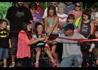 Eleven-year-old Bella Tiegs (center) prepared to do the honors at the ribbon-cutting event with help from her dad, Jeff Tiegs, and Jessica Kummer, Kylynn’s mother.