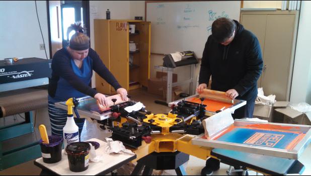 Chelsie Anger and Shawn Sauers work to apply color at the press.