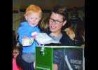 Heller Durand, two-year-old son of Scott and Emily Durand of Wabasha, gives a dollar bill to the cockatoo, which he in turn deposited into the Condor Fund box after Sunday’s Birdman Show.