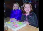Addie Quade, left, and Macey Haley were all smiles for a moment as they take a break from their bracelet making. Macey made nearly 400 bracelets  to donate to a fundraising effort for St. Jude and both young ladies were busy making more last Thursday evening at the Eagle View Bar and Grill in Minneiska. 
