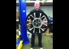Peter holds the large, 30-inch front wheel from the motorcycle he designed and won the Victory Design Challenge with.